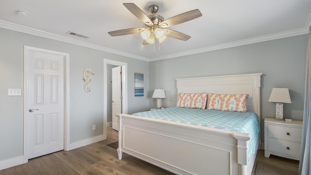 bedroom with wood finished floors, visible vents, and crown molding