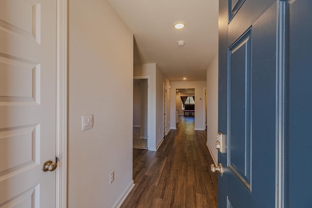 corridor with dark wood-type flooring and baseboards