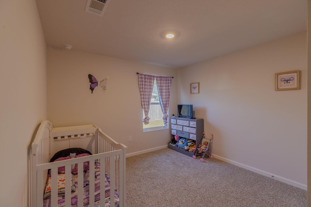 bedroom featuring a crib, baseboards, visible vents, and carpet flooring