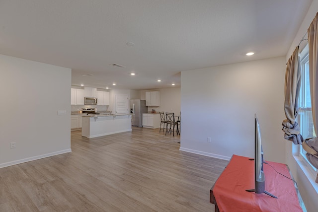 unfurnished living room with recessed lighting, light wood-style flooring, and baseboards