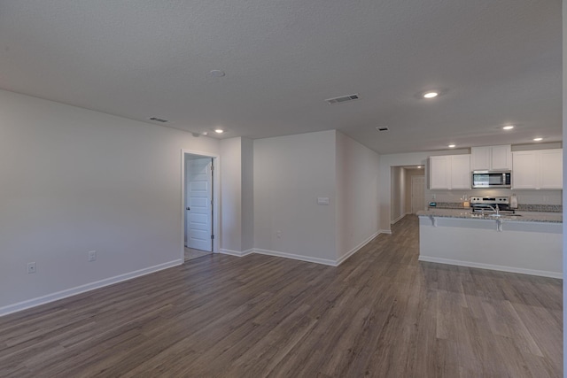 kitchen with dark wood-style flooring, white cabinetry, baseboards, open floor plan, and appliances with stainless steel finishes