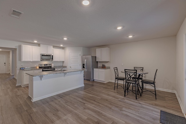 kitchen with stainless steel appliances, white cabinets, and visible vents