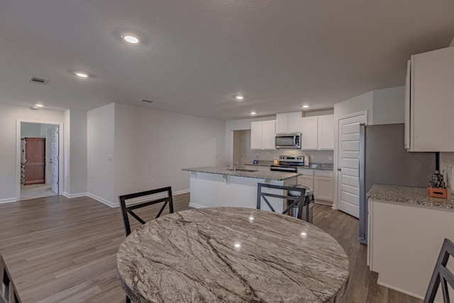 dining space with a textured ceiling, recessed lighting, visible vents, baseboards, and dark wood finished floors