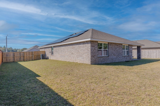 view of property exterior with solar panels, a lawn, a fenced backyard, and central air condition unit