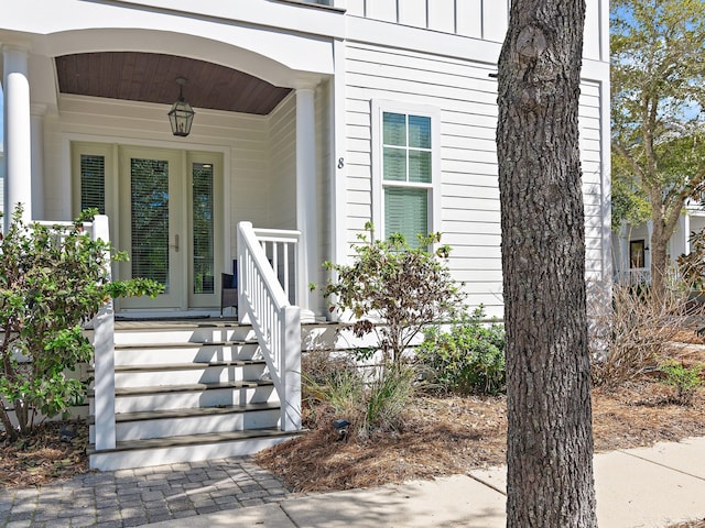 property entrance featuring covered porch and board and batten siding