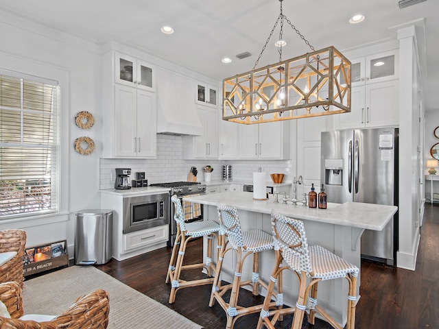 kitchen featuring light countertops, appliances with stainless steel finishes, dark wood-type flooring, and custom range hood