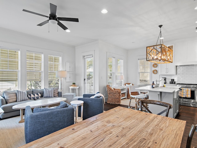 dining area featuring ornamental molding, recessed lighting, dark wood-style flooring, and ceiling fan with notable chandelier