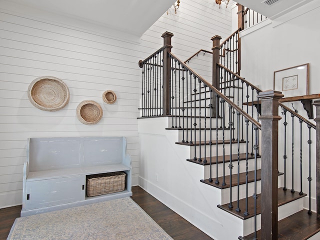 staircase with wood walls, wood finished floors, and baseboards