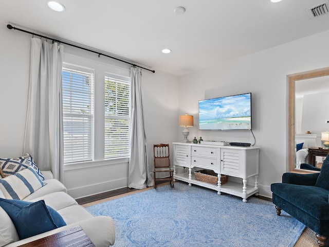 living room with recessed lighting, visible vents, baseboards, and wood finished floors