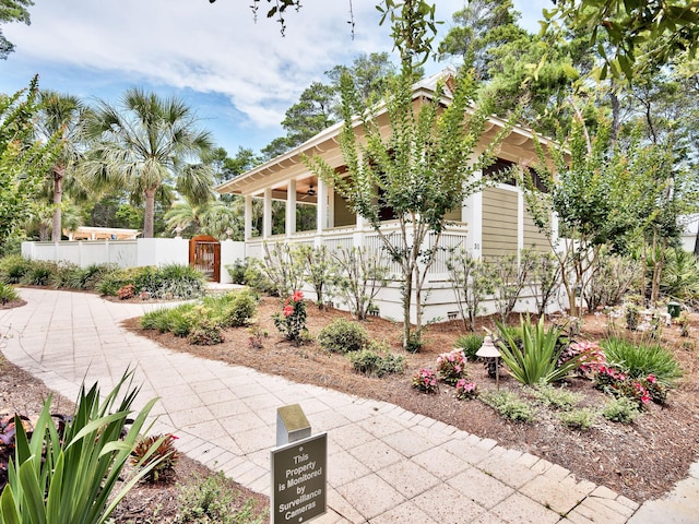 view of home's exterior featuring a gate, fence, and a ceiling fan