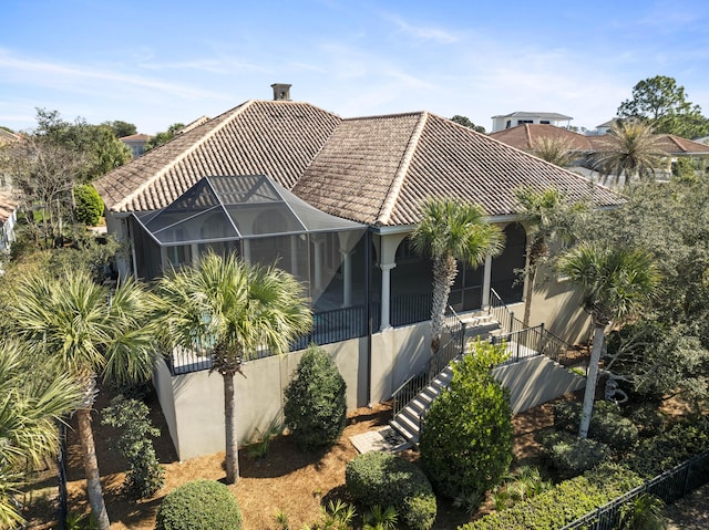 exterior space with glass enclosure, a tile roof, and stucco siding