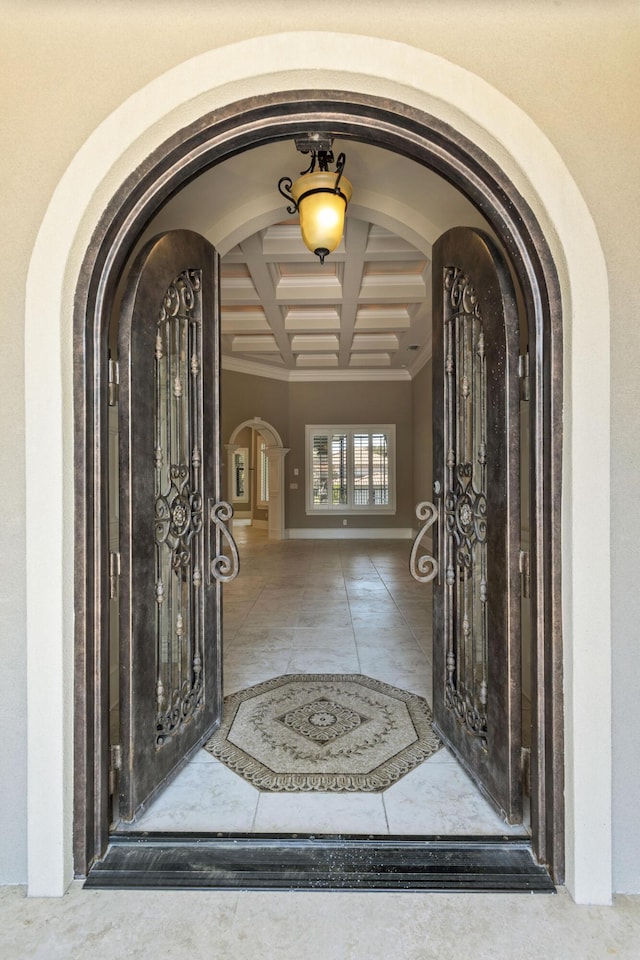 foyer entrance with arched walkways, coffered ceiling, baseboards, beam ceiling, and tile patterned floors