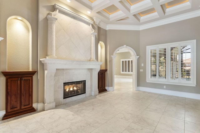 unfurnished living room with arched walkways, a tile fireplace, coffered ceiling, beamed ceiling, and baseboards