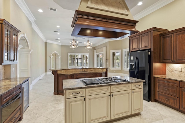 kitchen with visible vents, a kitchen island, cream cabinets, black appliances, and a sink