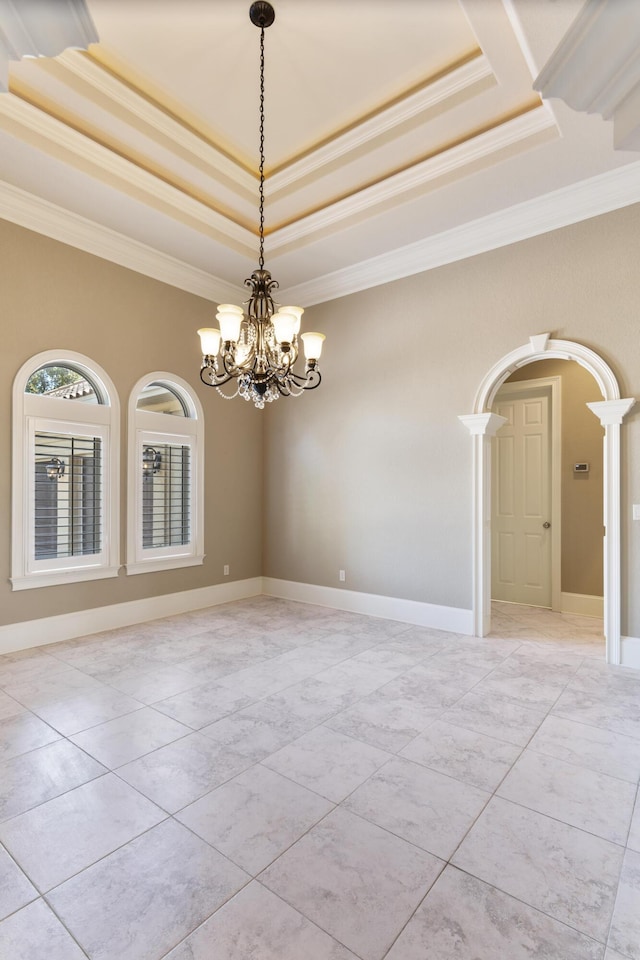 spare room featuring arched walkways, ornamental molding, a raised ceiling, and baseboards