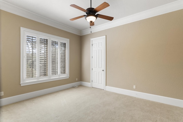 empty room featuring carpet flooring, crown molding, baseboards, and ceiling fan