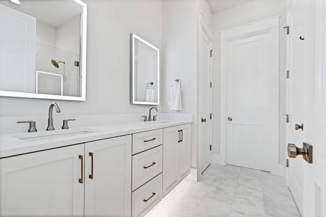 full bath featuring a stall shower, marble finish floor, a sink, and double vanity