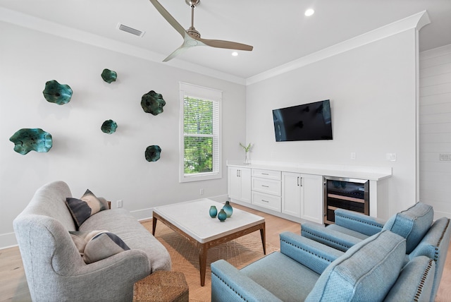 living room featuring ornamental molding, wine cooler, visible vents, and light wood-style flooring