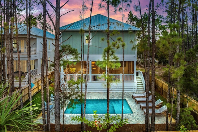 pool at dusk featuring stairway, fence, and an outdoor pool