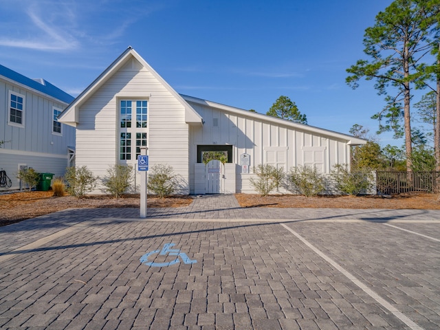 exterior space featuring uncovered parking, board and batten siding, fence, and a gate