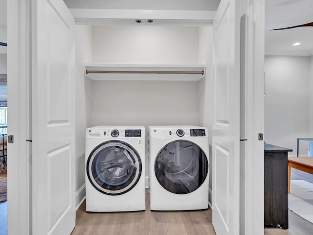 clothes washing area featuring laundry area, washing machine and dryer, and wood finished floors