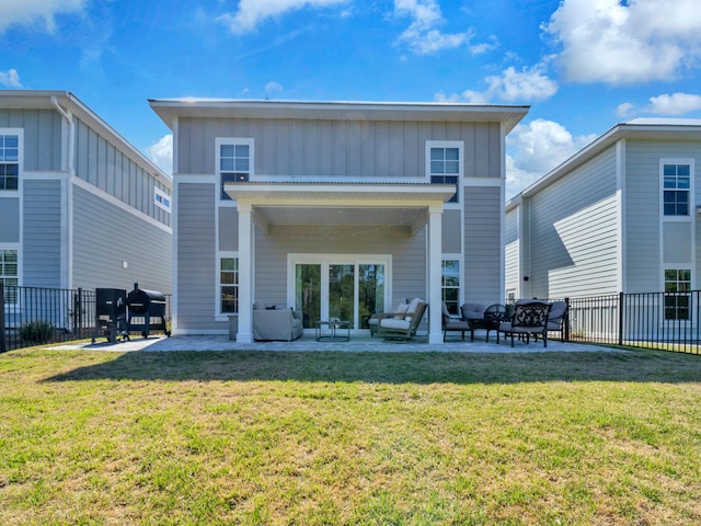 back of property with a yard, board and batten siding, a patio, and fence