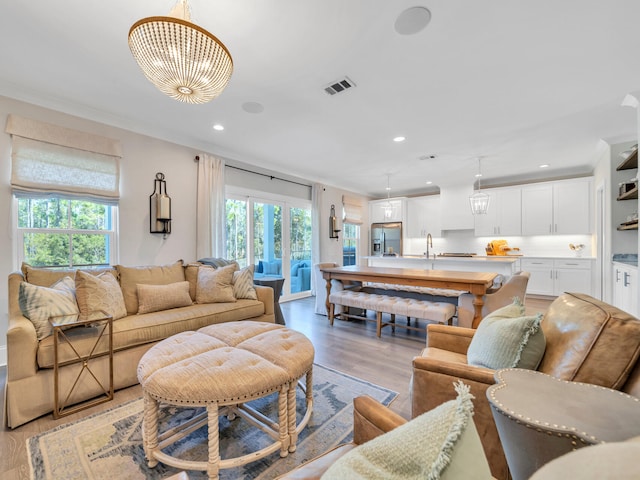 living room featuring ornamental molding, recessed lighting, visible vents, and light wood-style floors