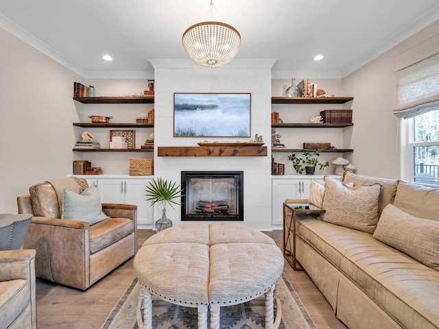 living area featuring light wood-style floors, recessed lighting, ornamental molding, and a glass covered fireplace