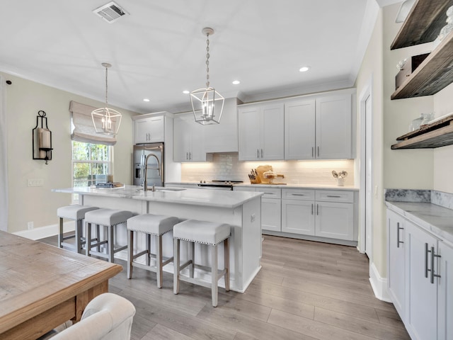 kitchen with a breakfast bar area, stainless steel appliances, a sink, visible vents, and decorative backsplash