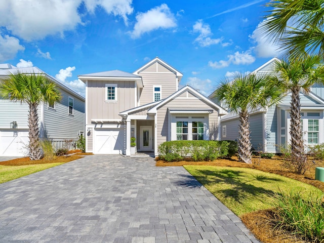 view of front of house featuring board and batten siding, a front yard, decorative driveway, and an attached garage