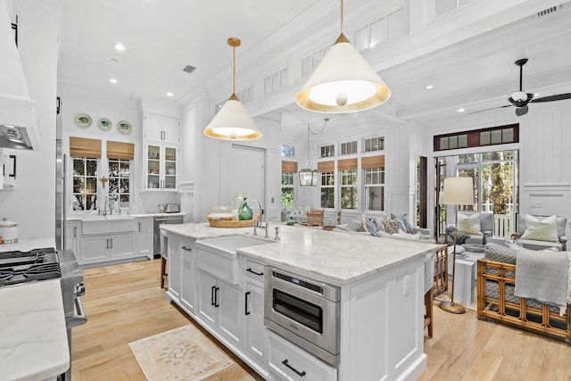 kitchen featuring stainless steel appliances, a sink, visible vents, open floor plan, and crown molding