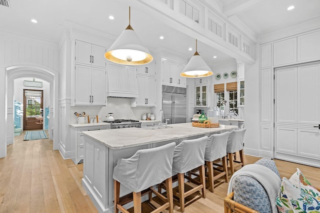 kitchen with ornamental molding, custom range hood, a sink, and built in refrigerator