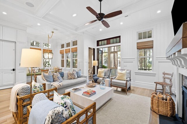 living room featuring beam ceiling, a fireplace, light wood finished floors, a decorative wall, and ornamental molding