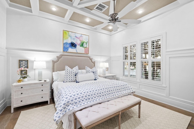 bedroom featuring coffered ceiling, visible vents, and a decorative wall