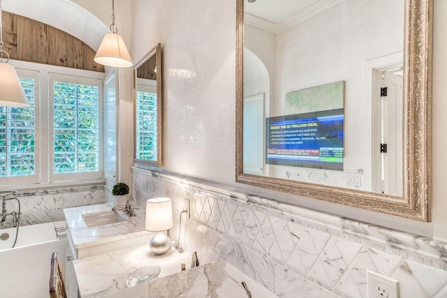 full bathroom featuring a soaking tub, ornamental molding, and a sink