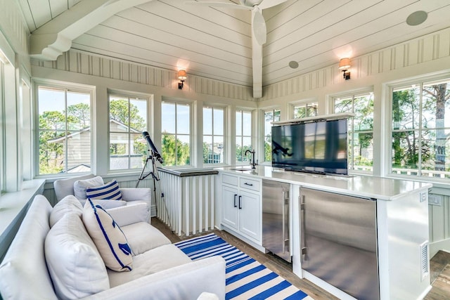 sunroom featuring vaulted ceiling, a healthy amount of sunlight, a sink, and wooden ceiling