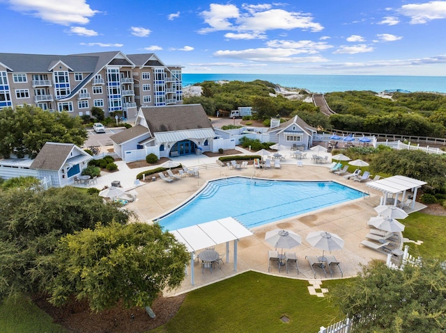 community pool with a water view, fence, and a patio