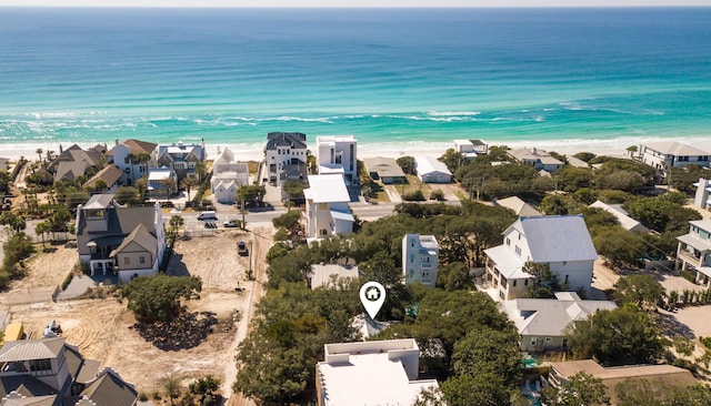 drone / aerial view featuring a water view, a residential view, and a beach view