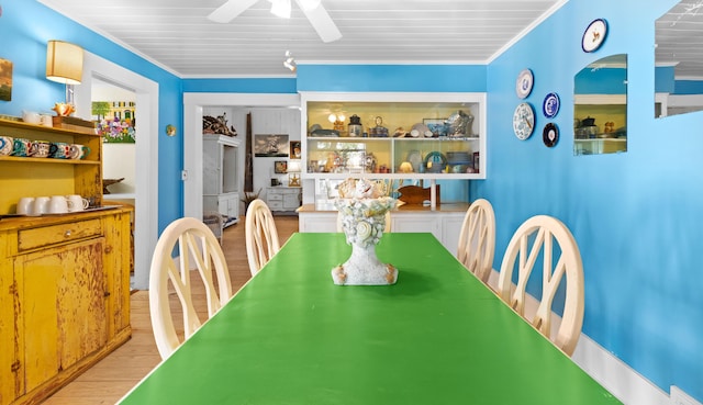 dining space with wood finished floors, a ceiling fan, and crown molding