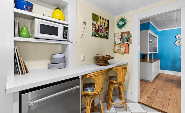 bar featuring ornamental molding, dishwasher, baseboards, and white microwave