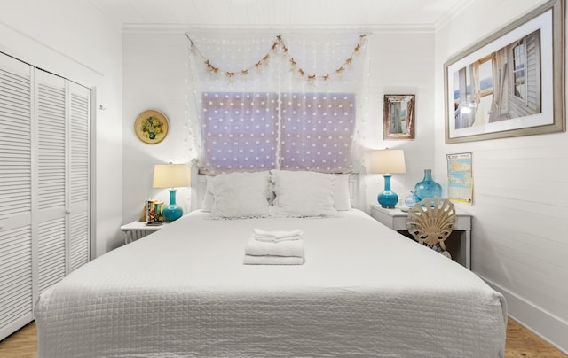 bedroom with a closet, ornamental molding, and wood finished floors