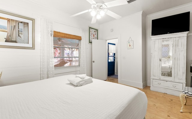 bedroom with baseboards, ornamental molding, a ceiling fan, and light wood-style floors