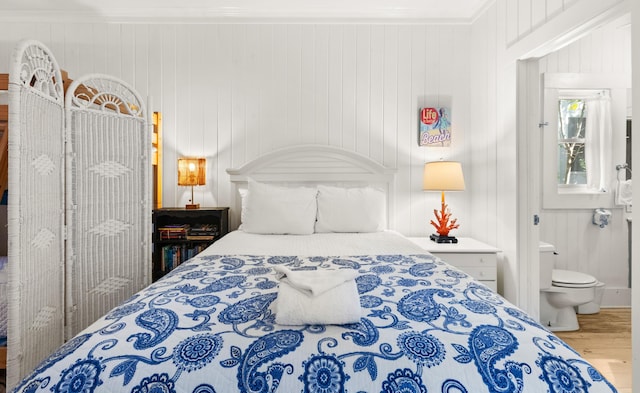 bedroom with wood finished floors and crown molding