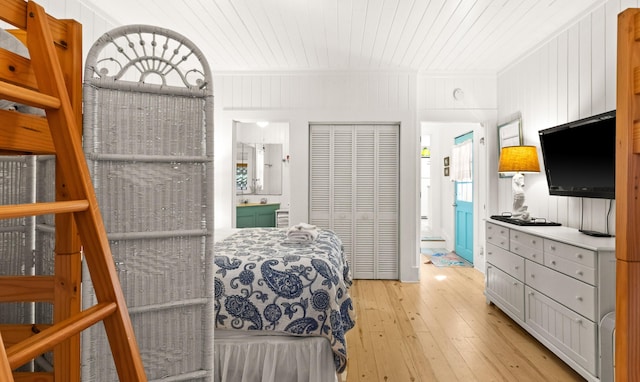 bedroom with a closet, light wood-type flooring, connected bathroom, and wood ceiling