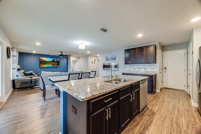 kitchen with tasteful backsplash, visible vents, light wood-type flooring, and a sink