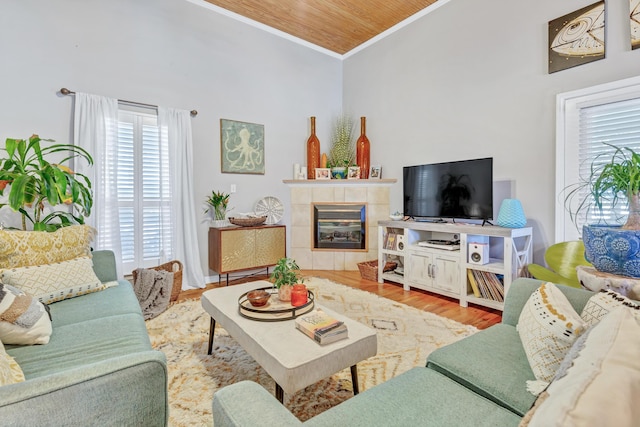 living room with wood finished floors, ornamental molding, wooden ceiling, and a tile fireplace