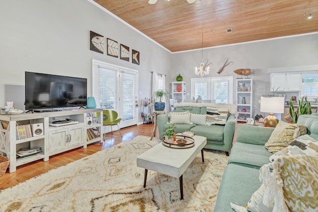 living area with crown molding, light wood-style floors, a towering ceiling, wooden ceiling, and a notable chandelier