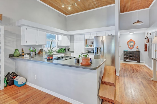 kitchen with appliances with stainless steel finishes, a high ceiling, a peninsula, and ornamental molding