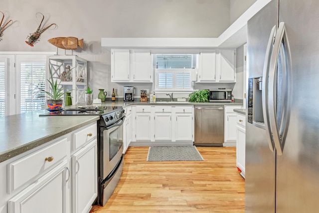 kitchen with light wood-style flooring, white cabinets, stainless steel appliances, and a sink