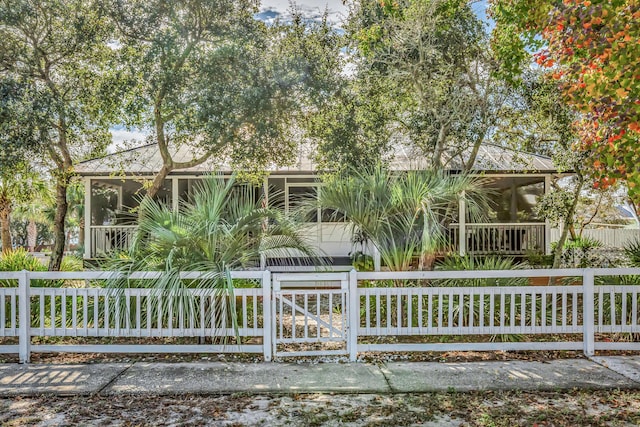 view of front of property featuring a fenced front yard and a sunroom